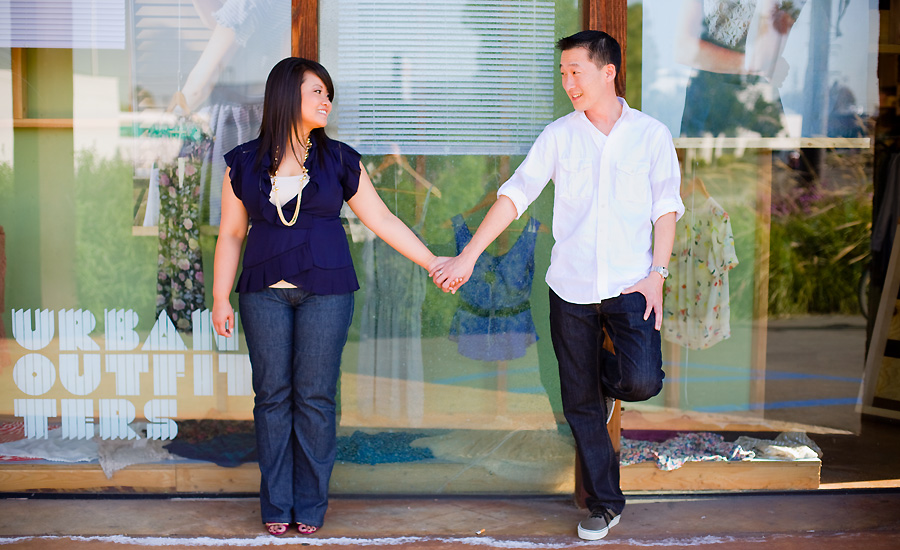 Picture of couple holding hands in front of clothing store in Costa Mesa for engagement pictures